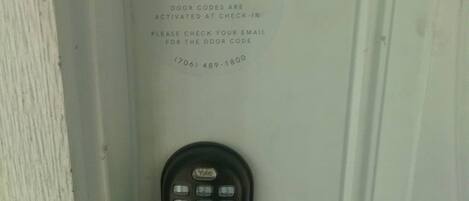 Puerta con teclado electrónico y letrero que dice 'Patriot Family Welcome' con instrucciones para el registro por correo electrónico.