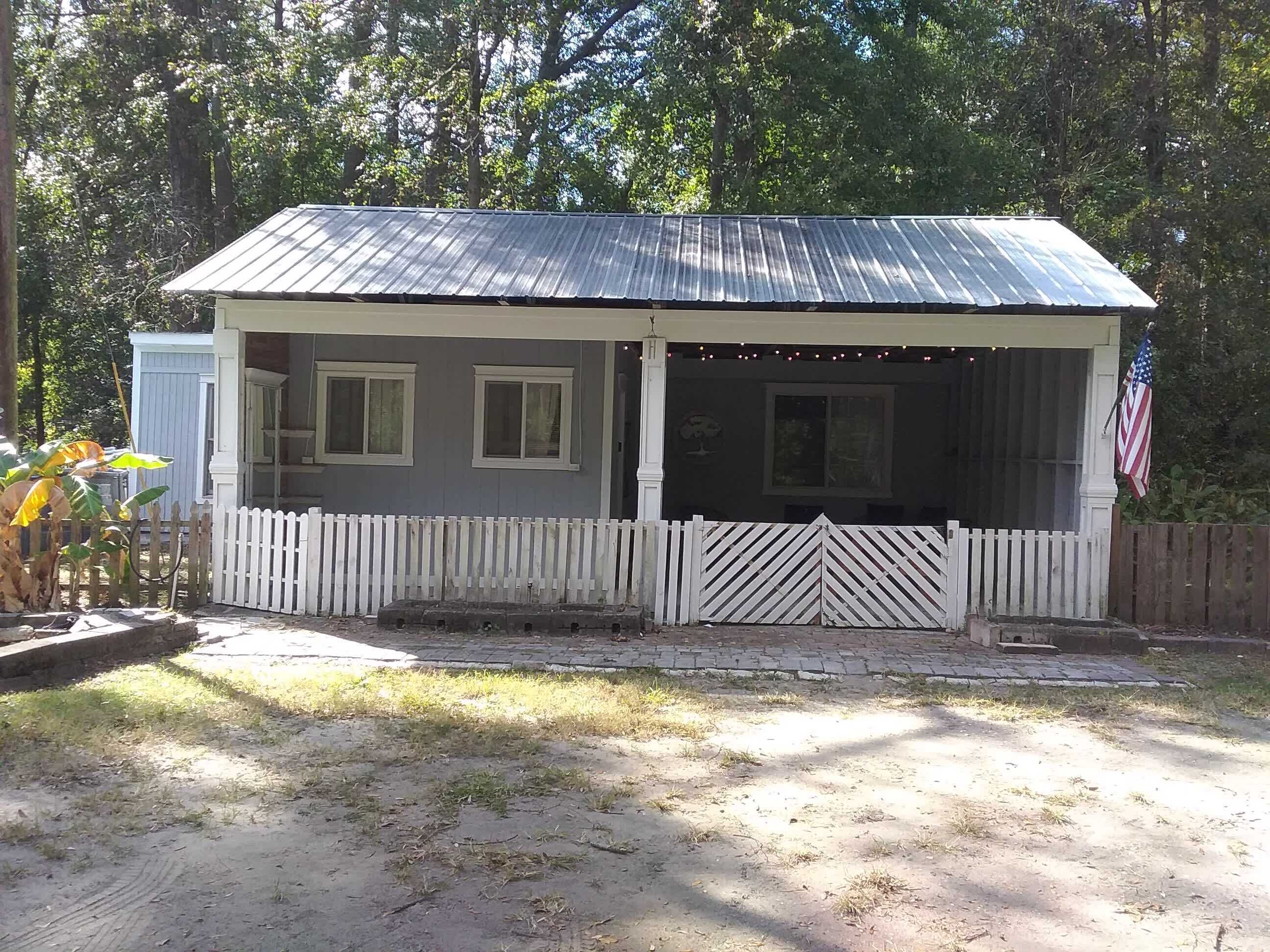 Uma casa térrea com varanda, um pequeno depósito e um quintal cercado.