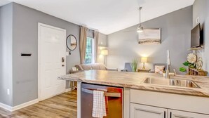 A modern kitchen with a marble countertop, built-in dishwasher, and a sink.