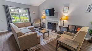 A living room with a sofa, armchairs, a fireplace, a TV, and a view of the outside. - Fenced Yard & BBQ Grill Near Dining, Parks & Shops (Savannah)