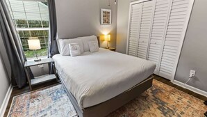 A bedroom with a bed, bedside table, lamp, and a large closet. - Fenced Yard & BBQ Grill Near Dining, Parks & Shops (Savannah)