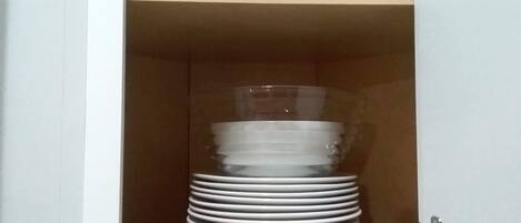Ein Schrank mit einer Reihe weißer Teller und einem durchsichtigen Glasbehälter.