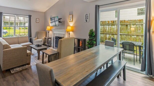 A spacious living room with a large wooden table, comfortable seating, and a sliding glass door leading to an outdoor patio. - Fenced Yard & BBQ Grill Near Dining, Parks & Shops (Savannah)
