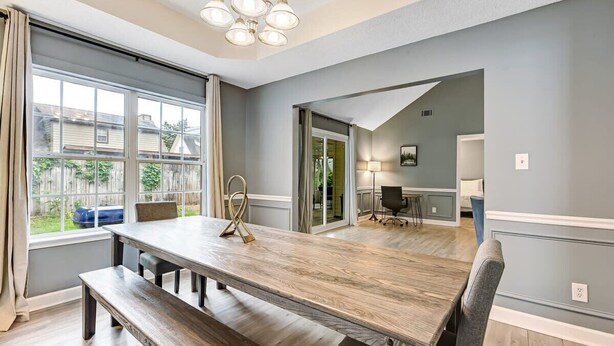 Ein Esszimmer mit einem großen Holztisch, Bänken und einer Chandelier.