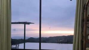 A room with a large window offering a view of a body of water and distant hills. - Magic Place Monteverde  (Monteverde)