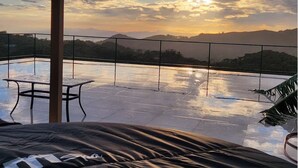 A rooftop terrace with a view of distant mountains and a sunset. - Magic Place Monteverde  (Monteverde)