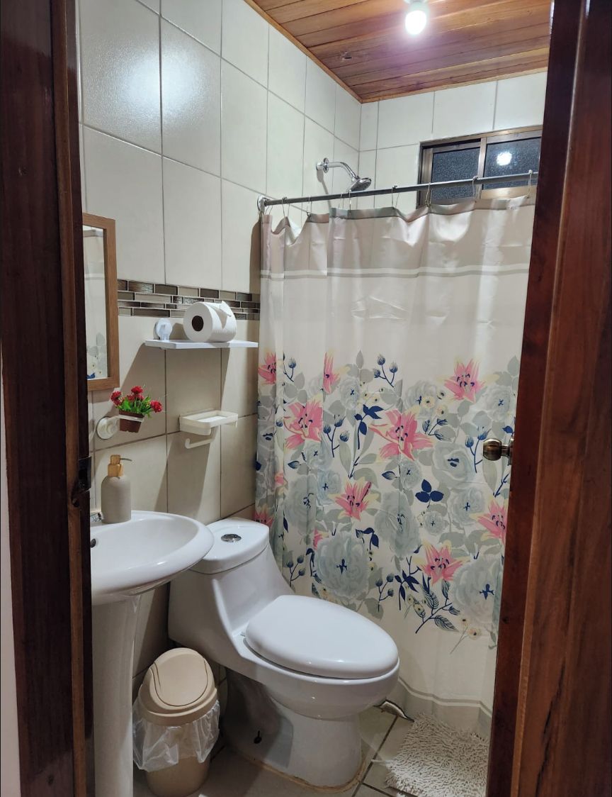 Un baño con inodoro, lavamanos y cortina de ducha.