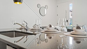 Une cuisine moderne dotée d’un îlot central, d’un évier intégré et d’un coin repas avec une table dressée pour deux personnes.