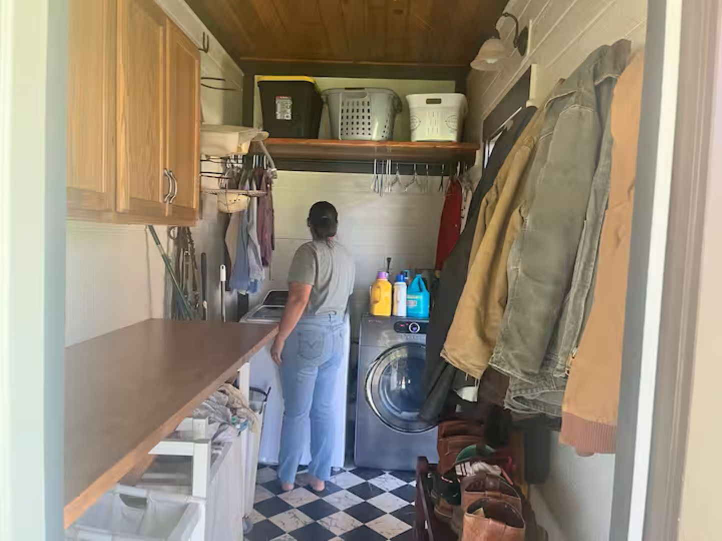 Een kleine wasruimte met een wasmachine, planken met wasmanden en een droogrek.