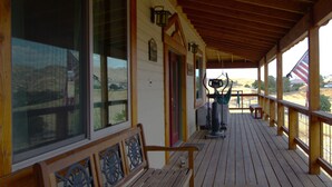 A wooden deck with a bench, large windows, and a view of a hill. - Sequoia Luxury Ranch House, View, Pool, horses, 30 min to Park, in Foothills (Exeter)