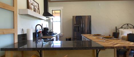 A modern kitchen with a bar area, wooden flooring, and a built-in stove.