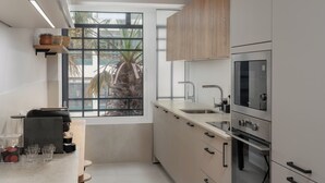 A modern kitchen with a large window, stainless steel appliances, and light wood cabinets. - Promenade II – Comfort and Elegance in Funchal (Funchal)