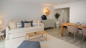 A modern living room with a sofa, coffee table, and dining table with chairs. - Promenade II – Comfort and Elegance in Funchal (Funchal)