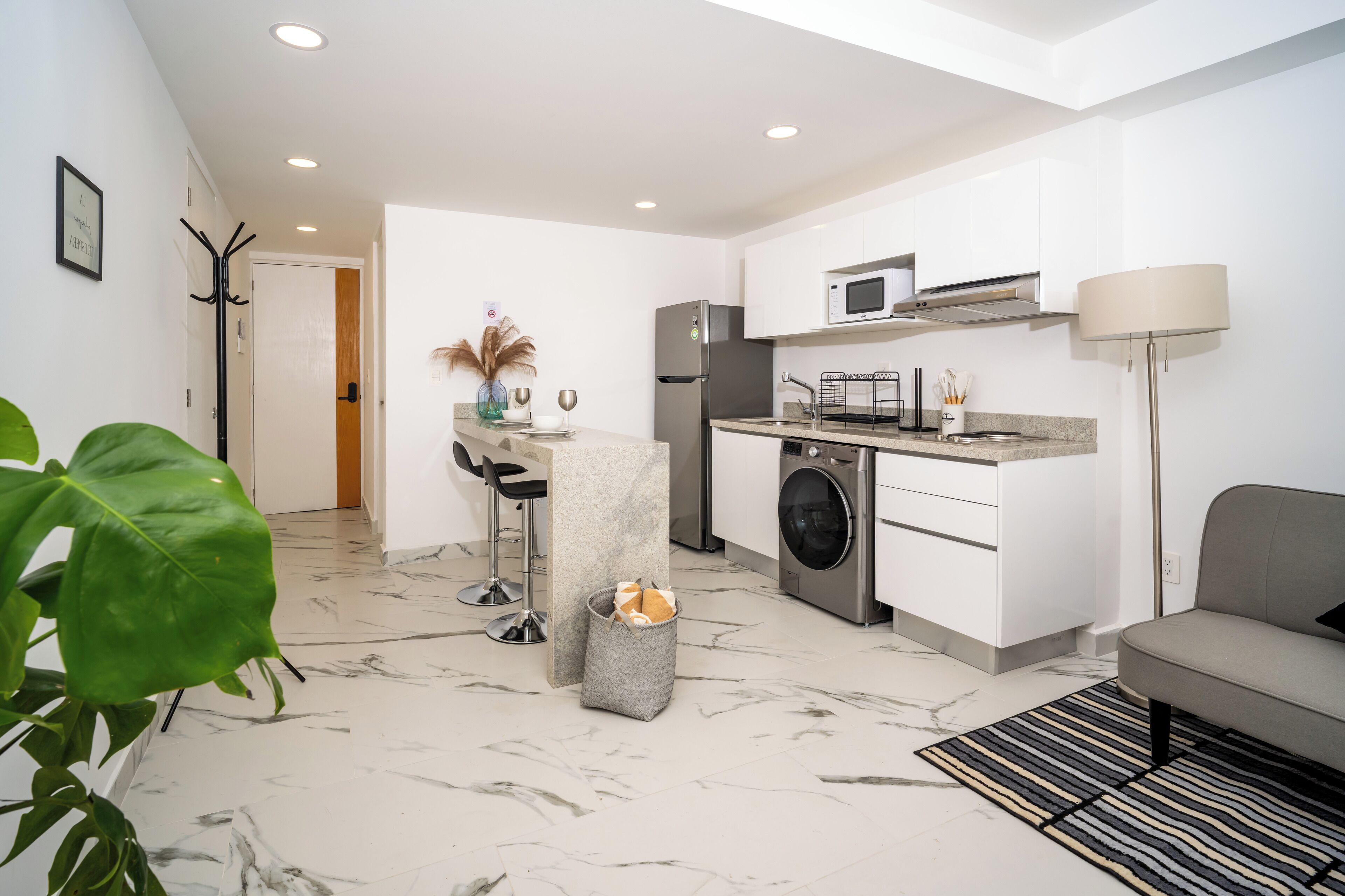 A modern kitchen with white cabinets, a built-in microwave, and a stainless steel refrigerator.