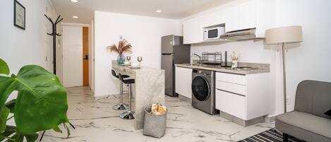 A modern kitchen with white cabinets, a built-in microwave, and a stainless steel refrigerator.