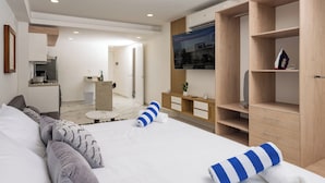 A modern hotel room with a large bed, a small desk, a TV, and a kitchenette. - Barcelona Condos Cancun (Canc ún)
