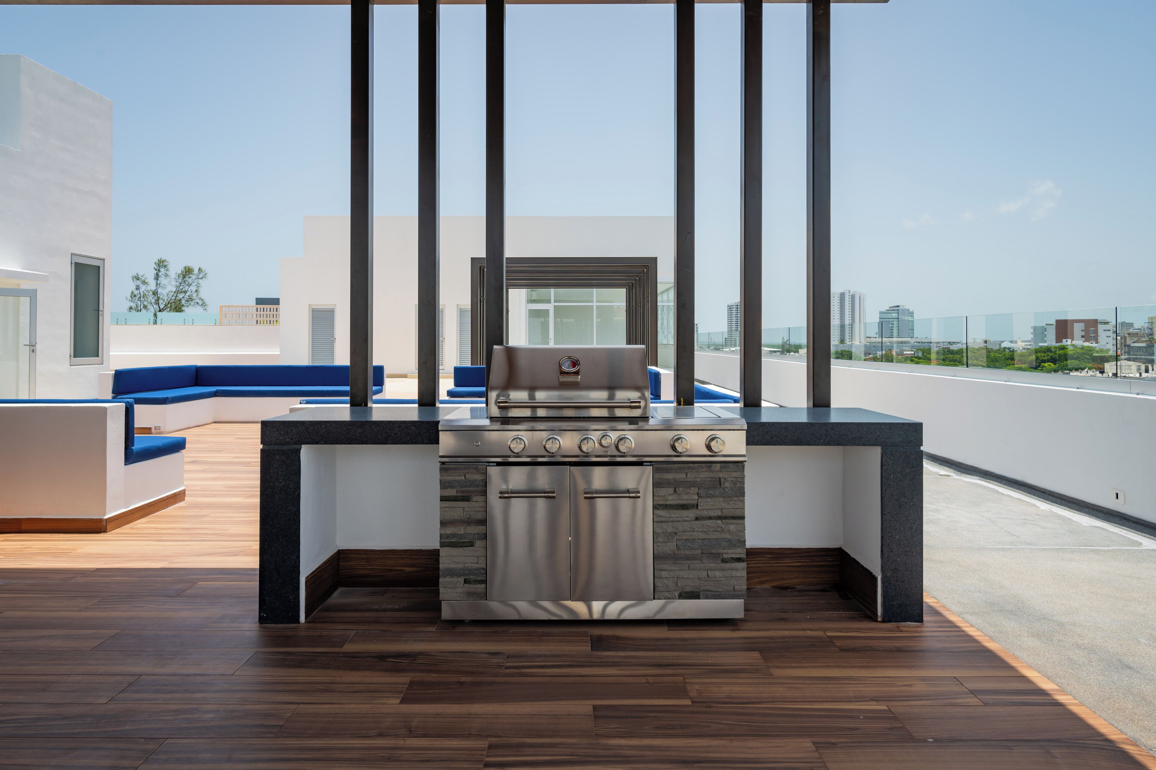 A modern outdoor kitchen with a built-in stove, seating area, and a view of the cityscape.