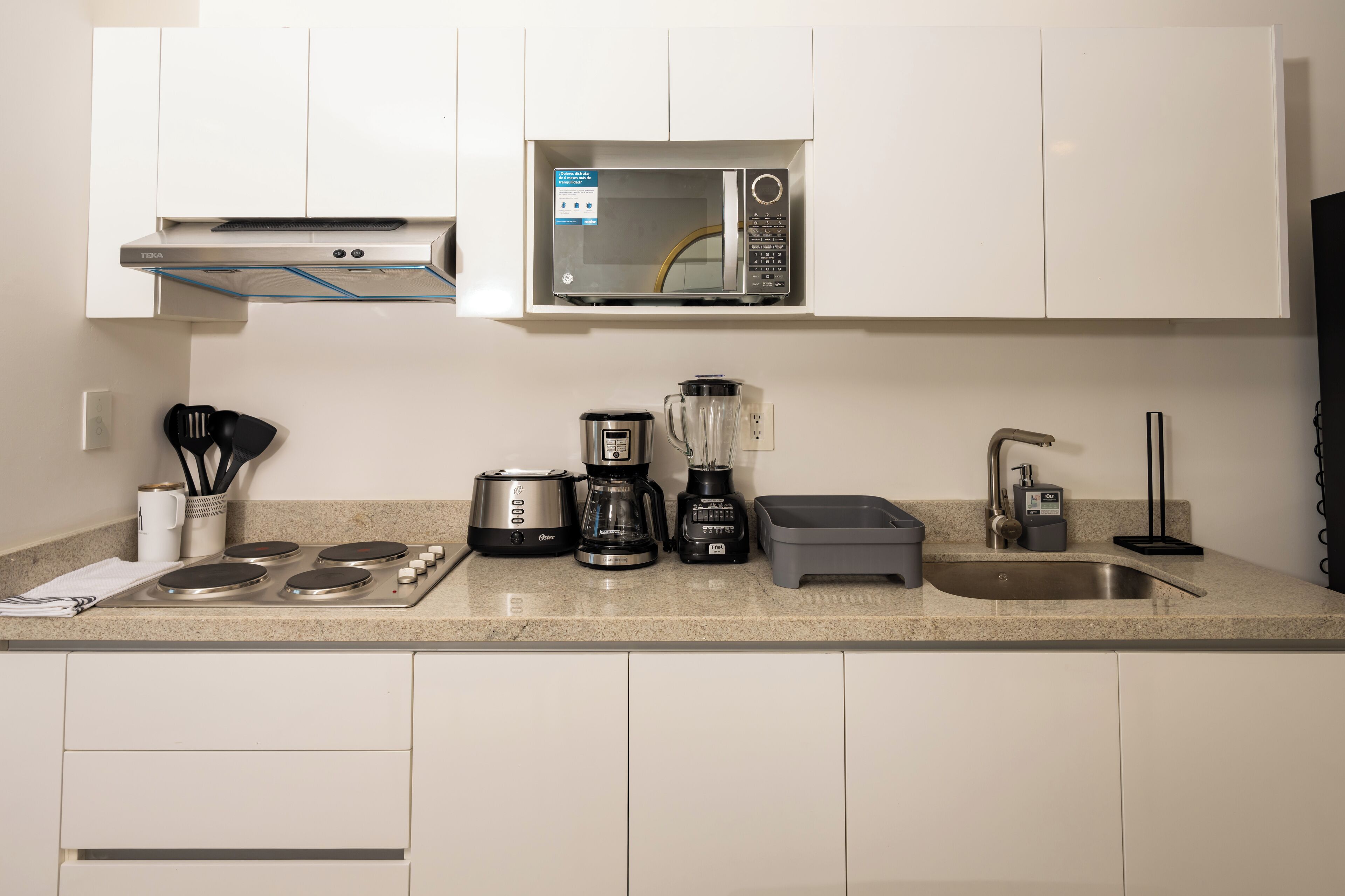 Eine moderne Küche mit Mikrowelle, Kaffeemaschine, Mixer und Spüle.