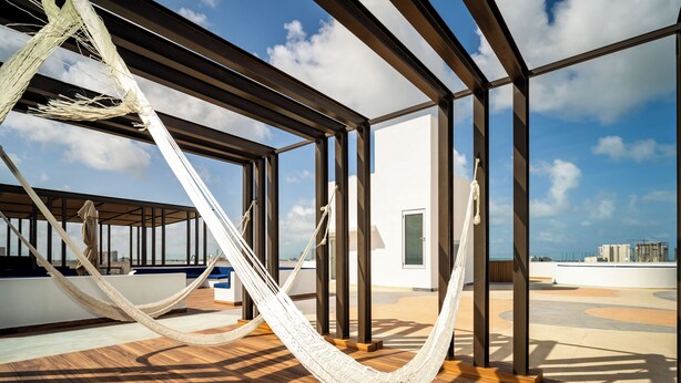 A hammock on a wooden deck with a view of the city skyline. - Barcelona Condos Cancun (Cancún)