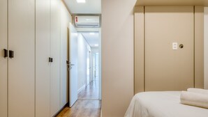 Ein Hotelzimmer mit einem Bett, einem Kleiderschrank und einem Gang zu weiteren Räumen.
