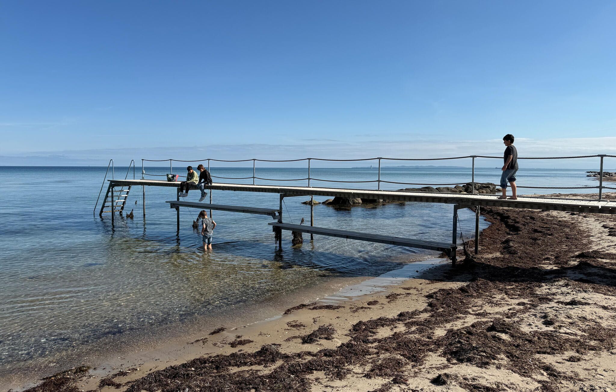 A pier extending into calm waters with clear skies.
