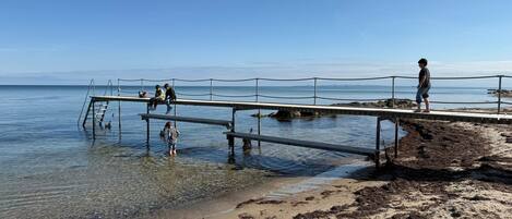 A pier extending into calm waters with clear skies.