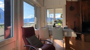 Un comedor con vistas a las montañas, una silla roja y una mesa con sillas.