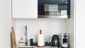 A modern kitchen with a stainless steel microwave, a coffee maker, and a kettle.
