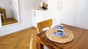 A wooden dining table with a woven placemat and two blue and white cups.
