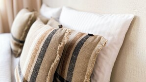 A bed with multiple pillows, including striped and plain ones.