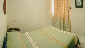 A single bed with a striped bedspread, a bedside table with a glass, and a window with a checkered curtain. - 2 bedroom house with swimming pool in Ixtapa (San José Ixtapa)