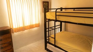 A bunk bed room with a checkered bedspread, a wooden dresser, and a window with curtains. - 2 bedroom house with swimming pool in Ixtapa (San José Ixtapa)