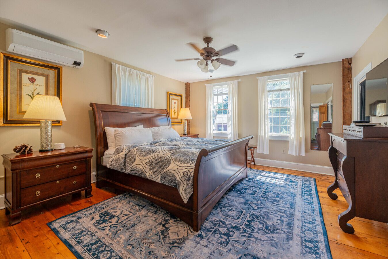 A bedroom with a wooden bed, a nightstand, a dresser, and a ceiling fan.
