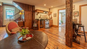 A spacious kitchen with wooden flooring, a dining area with a table and chairs, and a staircase leading to another level. - Historic Home with Colonial Charm in Manchester (Manchester)