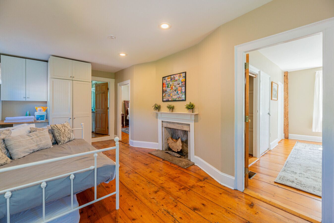 A bedroom with a bed, a fireplace, and wooden flooring.