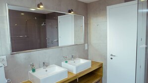 A modern bathroom with two white sinks, a large mirror, and a shower. - Suncity Luxury 2 bedroom apartment | Rooftop pool & Gym (Accra)