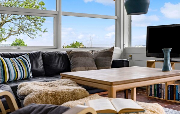 A living room with a black leather sofa, a wooden coffee table, and a bookshelf filled with books.