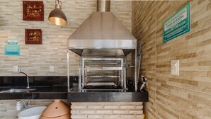 Eine Küche mit Backofen aus Ziegeln, Edelstahlgeräten und einer hängenden Leuchte.
