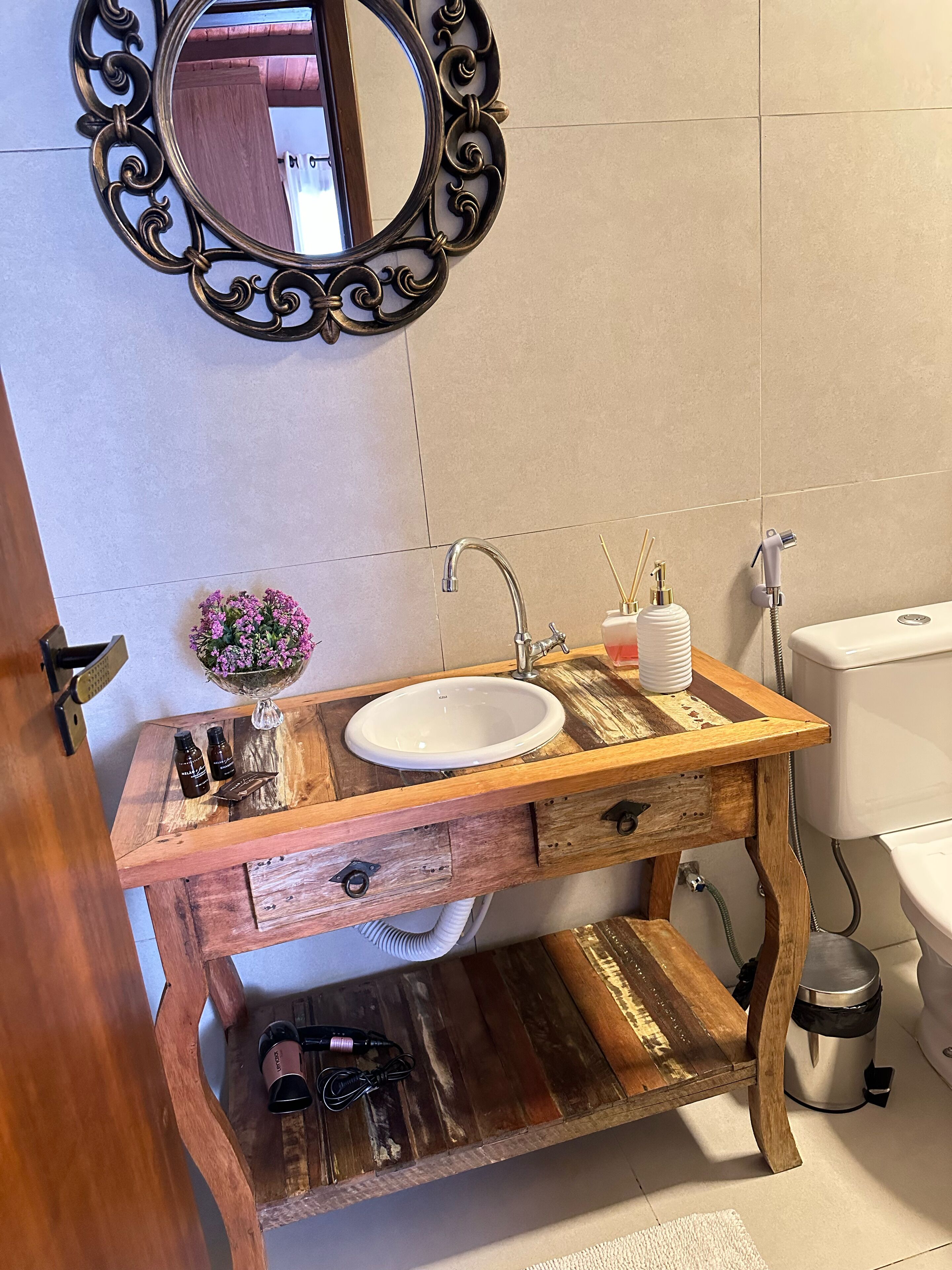 Une salle de bain avec un meuble-lavabo en bois, un lavabo blanc, un miroir doté d’un cadre orné et des toilettes.