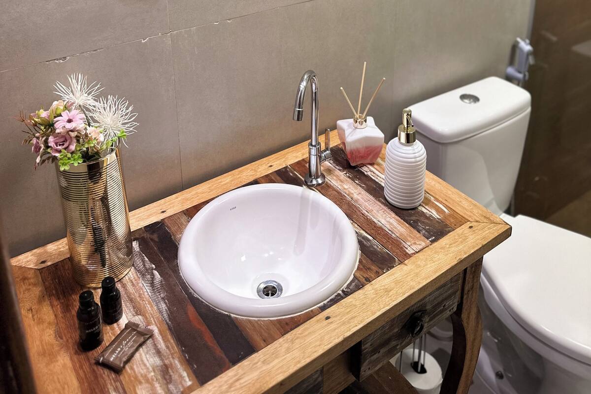A bathroom with a wooden vanity, white sink, and a mirror with ornate black frame.