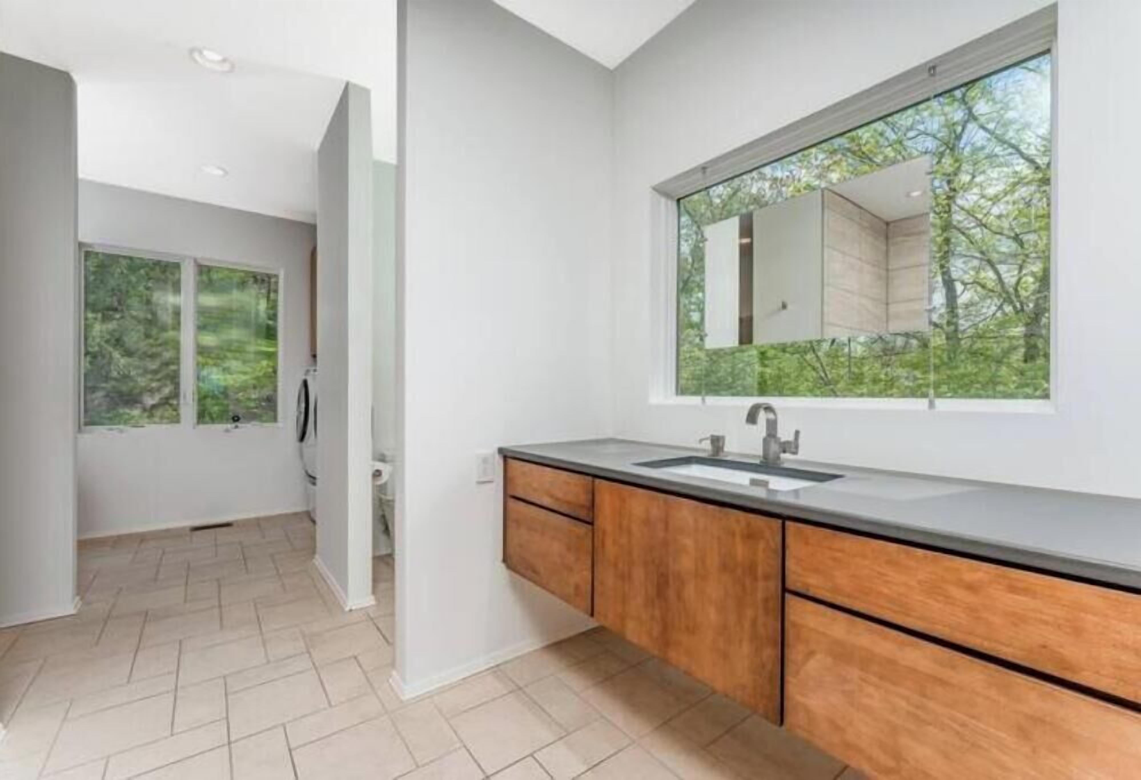 Un baño moderno con un espejo grande, armarios de madera y un lavabo.