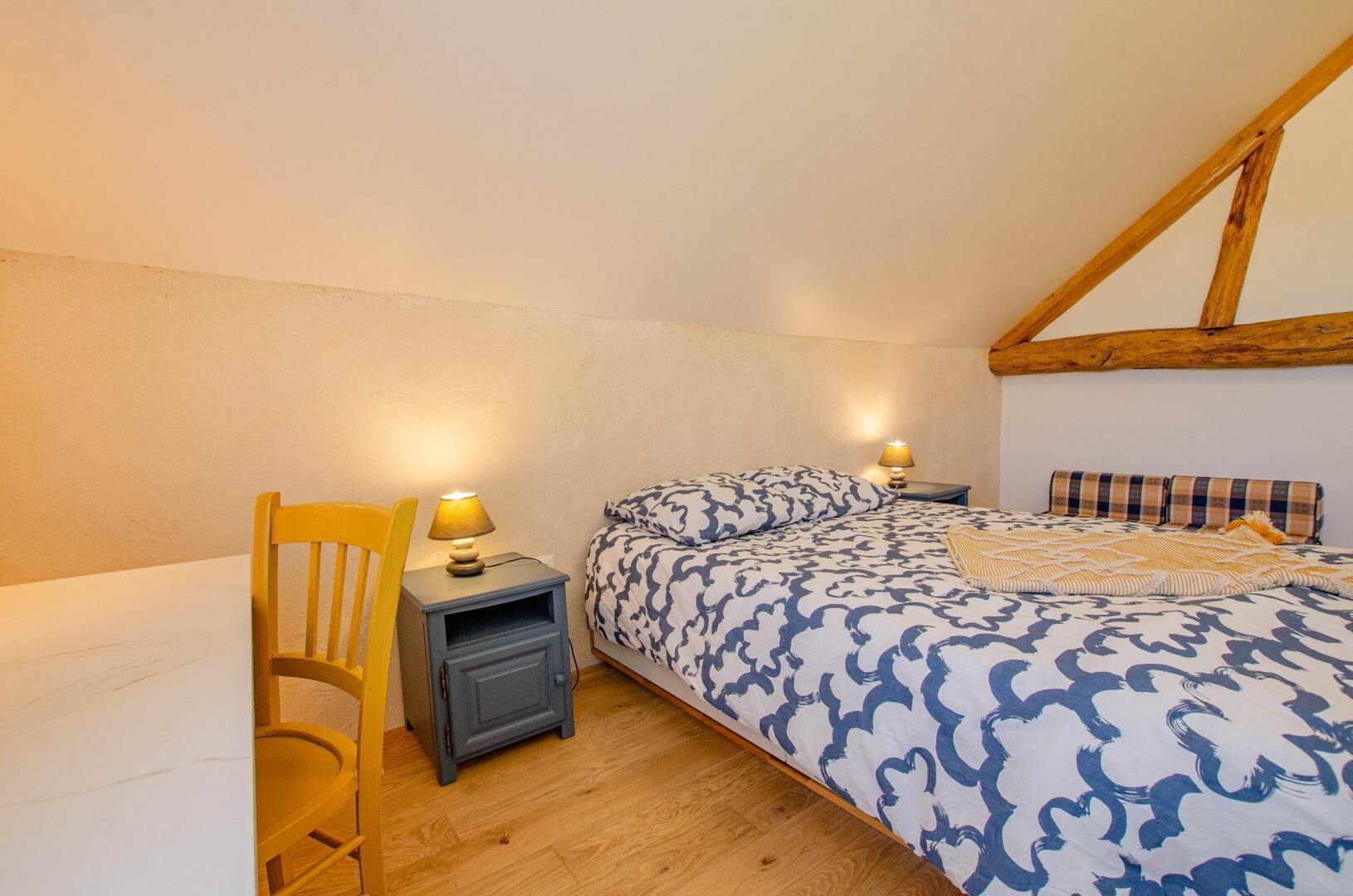 A bedroom with a bed, a chair, a nightstand, and a lamp.