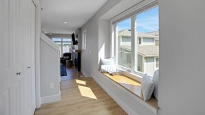 Ein Flur mit eingebautem Fensterbänkchen, einer Treppe und Blick auf Nachbarhäuser.
