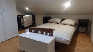 Un dormitorio con una cama, un radiador blanco y un pequeño banco de madera.