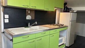 Una cocina con gabinetes verdes, un lavamanos blanco y un refrigerador blanco.
