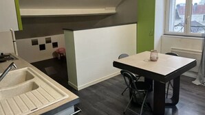 Una cocina moderna con un lavamanos, una mesa de comedor con sillas y una ventana con vistas a edificios.