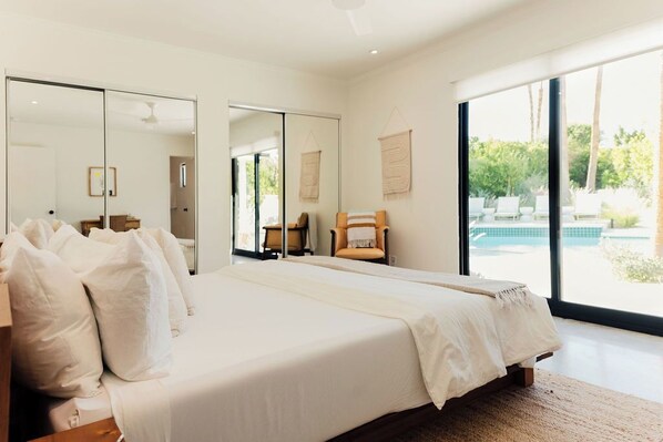 Un dormitorio moderno con una cama grande, una silla y vistas a una piscina.