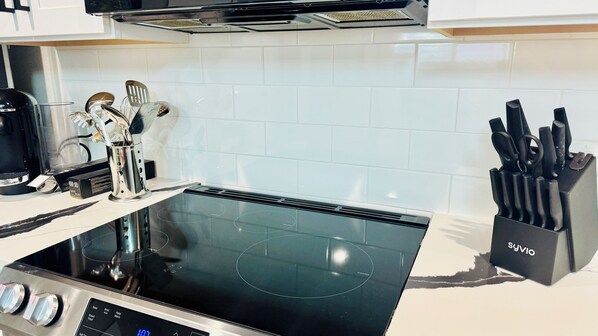 Eine moderne Küche mit einer schwarzen Induktionskochplatte, einer Kaffeemaschine und einem Messerblock.
