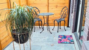 A patio area with a wooden fence, a potted plant, two metal chairs, a small round table, and a colorful rug. - 
Charming 2-bedroom house in wonderful Austin with WiFi, AC (Austin)