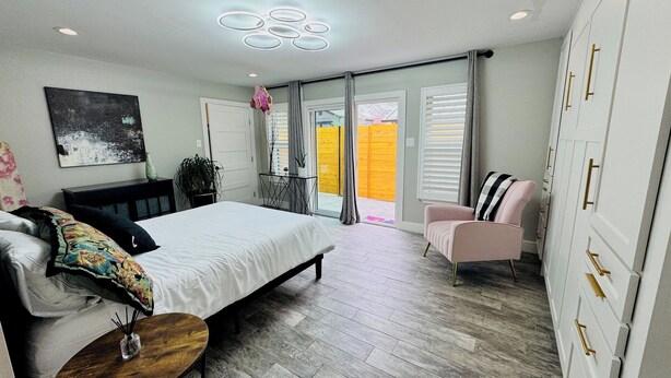 A bedroom with a bed, a chair, a bedside table, a plant, and a view of the outside. - 
Charming 2-bedroom house in wonderful Austin with WiFi, AC (Austin)